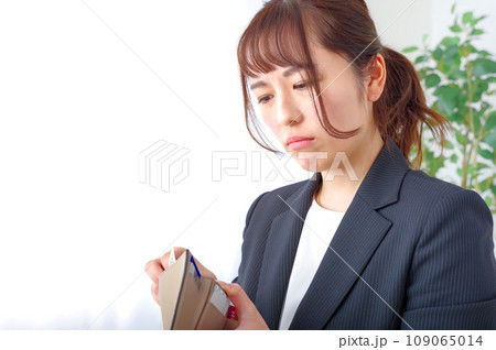 お金がないアピールをするスーツ姿の女性 109065014