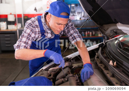 Positive man car mechanician repairing car in auto repair service 109069094