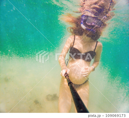 In an ethereal underwater scene, a pregnant woman gracefully floats, embodying the beauty of maternity beneath the tranquil surface of the sea 109069173