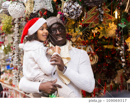 Man holding daughter, looking around at Christmas fair 109069317