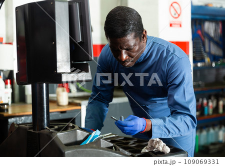 Afro american mechanic balancing tire with wheel balancing machinery Afro american mechanic balancing tire with wheel balancing machinery 109069331