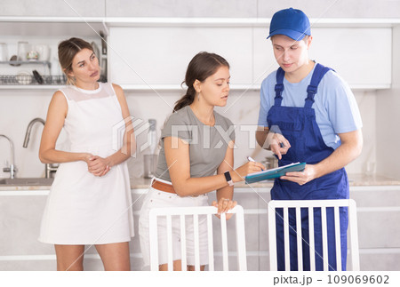 Female homeowners signing contract with cleaning company worker at home Female homeowners signing contract with cleaning company worker at home 109069602