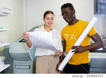 Man and woman check the print quality together in computer room 109069701