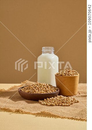 Lots of soybeans contained inside wooden bowl and dish. Glass bottle of soybean milk featured. Soy is a very special ingredient, and its uses seem to be never-ending Lots of soybeans contained inside wooden bowl and dish. Glass bottle of soybean milk featured. Soy is a very special ingredient, and its uses seem to be never-ending 109070642
