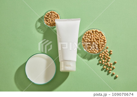 Three glass petri dishes containing soybean seeds and milk surrounded a beauty tube without label. Soybean (Glycine max) can boost the production of collagen Three glass petri dishes containing soybean seeds and milk surrounded a beauty tube without label. Soybean (Glycine max) can boost the production of collagen 109070674