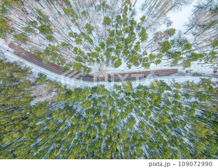 Flight over the winter mountains with road serpentine and pine forest. Top down view. Landscape photography Flight over the winter mountains with road serpentine and pine forest. Top down view. Landscape photography 109072990