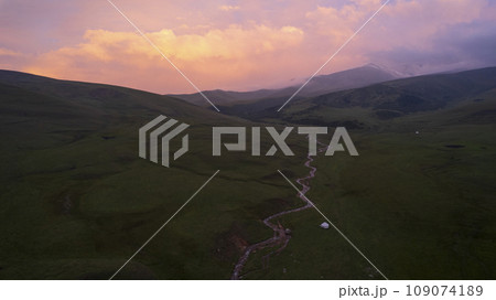Pink-purple sunset in mountains with green fields Pink-purple sunset in mountains with green fields 109074189