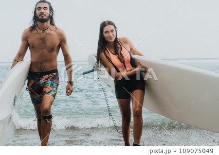 Sea woman and man on sup. Silhouette of happy young woman and man, surfing on SUP board, confident paddling through water surface. Idyllic sunset. Active lifestyle at sea or river. Sea woman and man on sup. Silhouette of happy young woman and man, surfing on SUP board, confident paddling through water surface. Idyllic sunset. Active lifestyle at sea or river. 109075049
