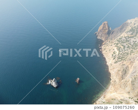 Aerial view from above on calm azure sea and volcanic rocky shores. Small waves on water surface in motion blur. Nature summer ocean sea beach background. Nobody. Holiday, vacation and travel concept 109075260