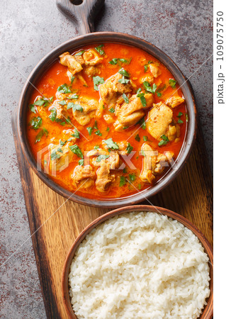 Traditional spicy Lahori Chicken Curry served with rice closeup on the wooden board on the table. Vertical top view 109075750