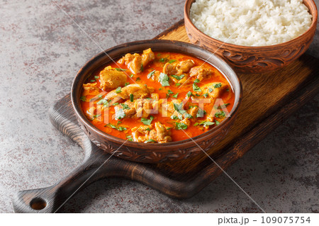 Lahori chicken curry is filled with chicken, ginger, cinnamon, cardamom, peppercorns, coriander, cumin, cilantro served with rice closeup on the wooden board. Horizontal 109075754
