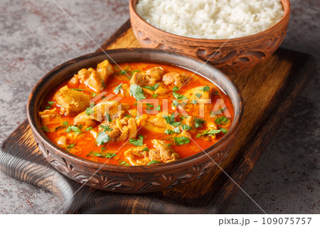 Chicken lahori is a traditional Pakistani chicken curry hailing from the city of Lahore served with rice closeup on the wooden board. Horizontal 109075757