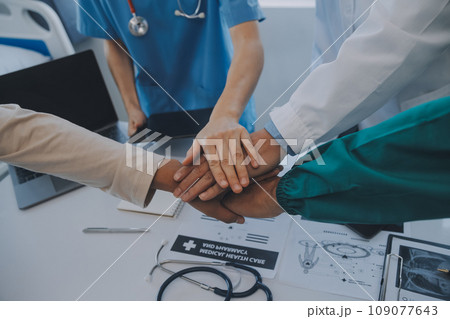 Multiracial team of doctors discussing a patient standing grouped in the foyer looking at a tablet computer, close up view 109077643