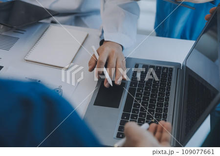 Multiracial team of doctors discussing a patient standing grouped in the foyer looking at a tablet computer, close up view 109077661