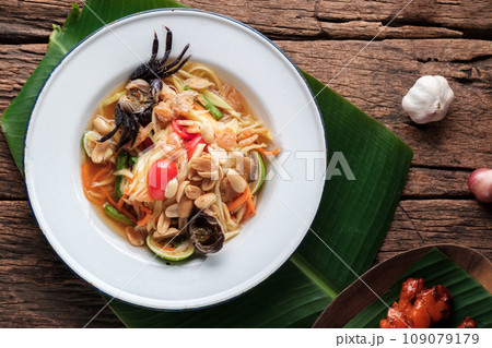 Spicy Papaya Salad with Salted Crab in White Dish, (Som Tam) on Banana Leaf Spicy Papaya Salad with Salted Crab in White Dish, (Som Tam) on Banana Leaf 109079179