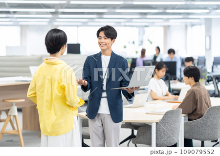 オフィスで打ち合わせをする新入社員の若い男女のエンジニア オフィスで打ち合わせをする新入社員の若い男女のエンジニア 109079552