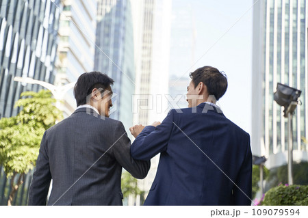 two asian corporate executives bumping elbows while walking in street two asian corporate executives bumping elbows while walking in street 109079594
