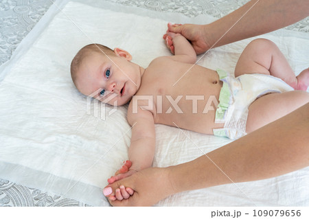 Mother's hands do gymnastics with the baby. Arms spread to the sides 109079656