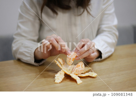みかんの白い筋を取って食べる女性 みかんの白い筋を取って食べる女性 109081348