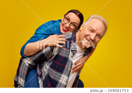 Smiling, beautiful happy senior woman, couple, man and woman in casual clothes posing against yellow studio background. Valentine's Day Smiling, beautiful happy senior woman, couple, man and woman in casual clothes posing against yellow studio background. Valentine's Day 109081753