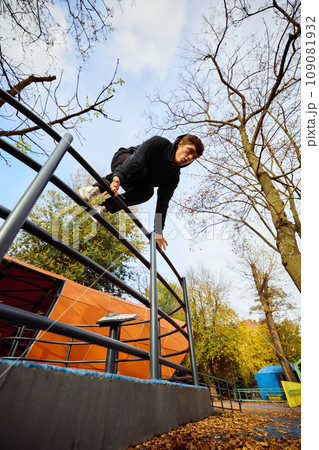 Free runner, young guy making flip over parking lot, practice Parkour in public park among over sky view. Eye fish filter. 109081932