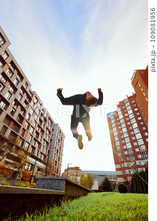 Fish eye effect photo of young man, guy performing insane jumps and breathtaking salto in air in action. Extreme sport activity, free running. Fish eye effect photo of young man, guy performing insane jumps and breathtaking salto in air in action. Extreme sport activity, free running. 109081956