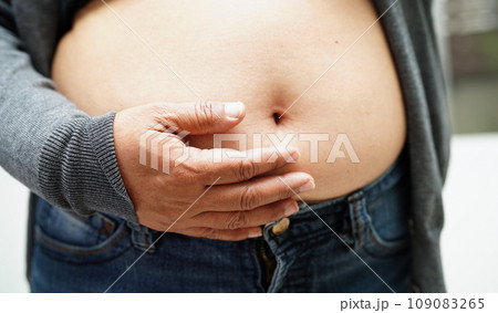 Asian woman show fat belly big size overweight and obesity at office. 109083265