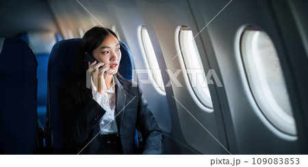 Successful Asian business woman, Business woman working in airplane on laptop computer and looking out the window along with talking on the phone 109083853