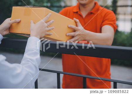 Asian Woman Receiving Product from delivery man at Home, Young Owner Woman Order Product from Smartphone Application, Woman with Online Business or SME Concept. 109085822