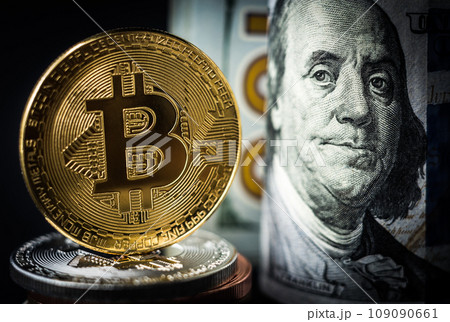 Bitcoin coin standing in front of dollar bills Bitcoin coin standing in front of dollar bills 109090661