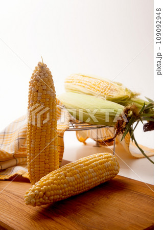 Cutting board with two cobs sweet corn on white wooden background.. 109092948