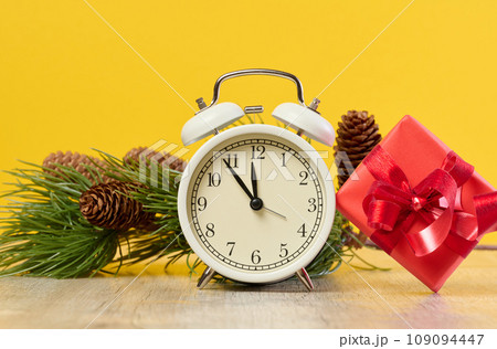 Alarm clock and stack of red gift boxes on yellow background 109094447