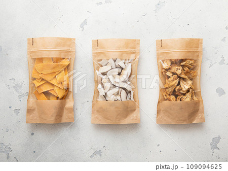 Packages with dried sweet mango coconut and pineapple slices chip on light background. Packages with dried sweet mango coconut and pineapple slices chip on light background. 109094625