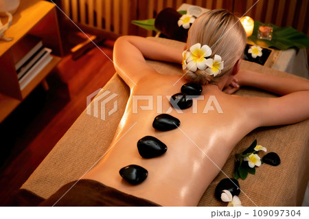 Hot stone massage at spa salon in luxury resort with warm candle light.Quiescent 109097304
