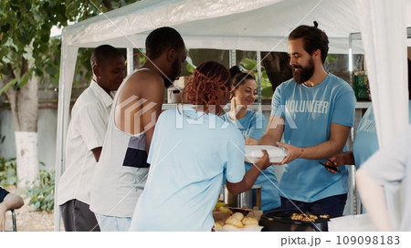 Multiethnic charitable organization provides free food and provisions to the homeless and crippled. Black woman wearing a blue t-shirt aiding a helpless, crutch-wielding african american guy. Multiethnic charitable organization provides free food and provisions to the homeless and crippled. Black woman wearing a blue t-shirt aiding a helpless, crutch-wielding african american guy. 109098183