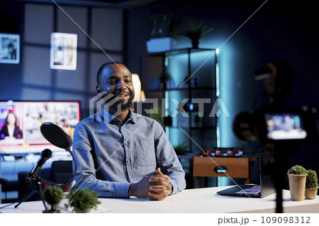 Smiling influencer preparing to start recording content for social media channel. BIPOC internet show host ready to begin filming using professional camera and microphone 109098312