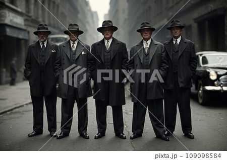 A group of menacing gangsters in the 1930s exude an aura of danger and lawlessness as they stand on the gritty streets of the city. Adorned in sharp suits and fedora hats. 109098584