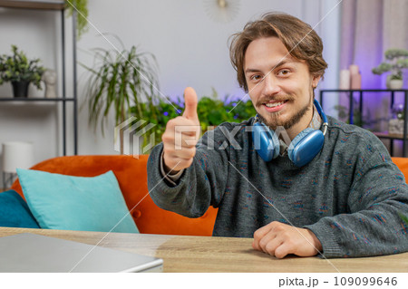 Happy Caucasian young man looking approvingly at camera show thumbs up like positive sign good news Happy Caucasian young man looking approvingly at camera show thumbs up like positive sign good news 109099646