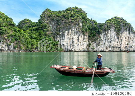 ベトナム　奇岩が続くハロン湾で手漕ぎのボートを操る船頭さん 109100596