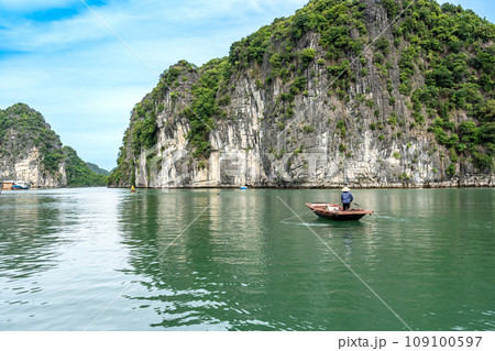 ベトナム　奇岩が続くハロン湾で手漕ぎのボートを操る船頭さん 109100597