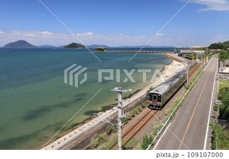瀬戸内を走るJR予讃線の普通列車と香川県三豊市三野町の海上に浮かぶ子供の守り神「津嶋神社」 109107000