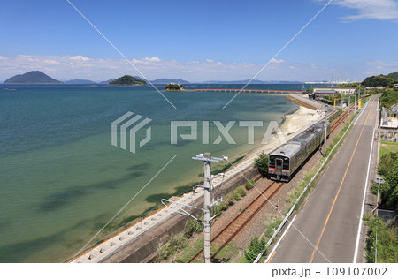 瀬戸内を走るJR予讃線の普通列車と香川県三豊市三野町の海上に浮かぶ子供の守り神「津嶋神社」 109107002