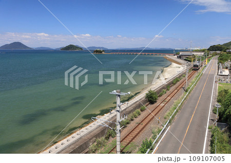 瀬戸内を走るJR予讃線の普通列車と香川県三豊市三野町の海上に浮かぶ子供の守り神「津嶋神社」 109107005