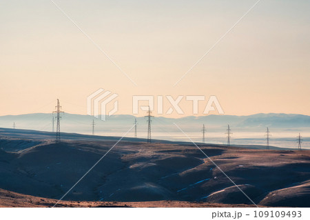 High voltage electric pole on mountain hill among remote wilderness in the sunrise at rural scene of Altai region. 109109493