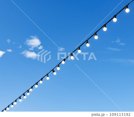 Lightbulbs hanging on wire over blue sky background 109113192