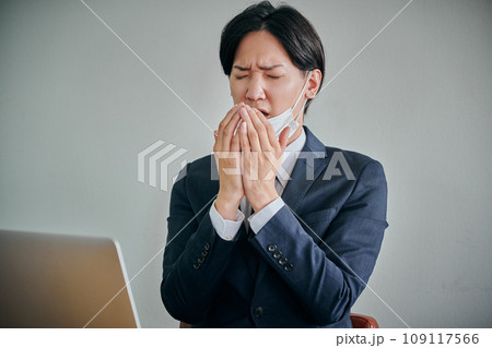 手で口を覆うマスク姿の男性会社員 109117566