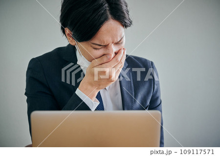 手で口を覆うマスク姿の男性会社員 109117571