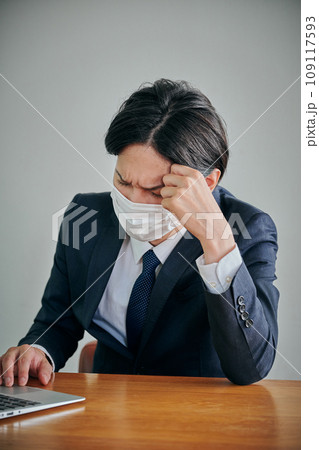 おでこに手を当てるマスク姿の男性会社員 109117593