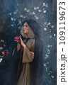 Stepmother witch gives poisoned red apple.Woman as witch in black offers red apple as symbol of temptation, poison. Fairy tale, white snow wizard concept. Spooky Halloween, cosplay. 109119673