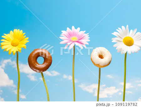 Colorful glazed donuts and daisy flowers in row against blue sky Colorful glazed donuts and daisy flowers in row against blue sky 109119782
